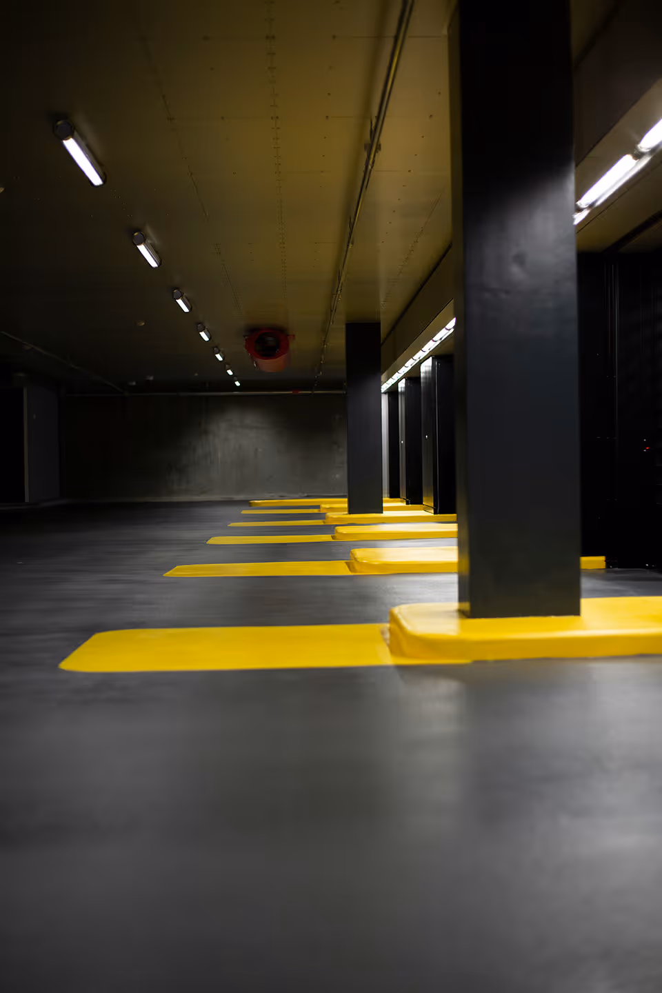 Tiefgarage mit grauem Boden, gelben Parkmarkierungen.