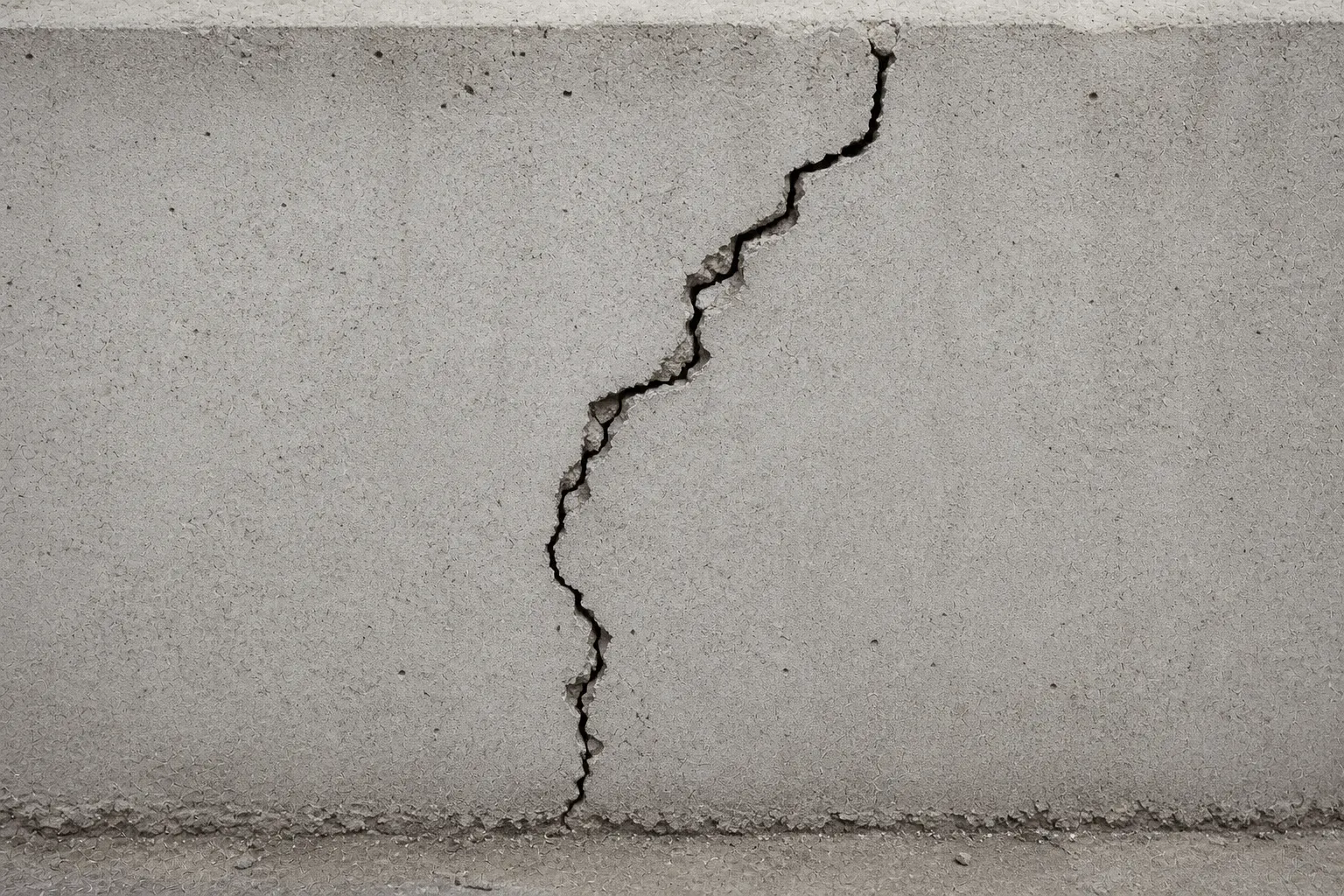 Durchgehender Riss mit unregelmäßigem Verlauf in einer Betonwand